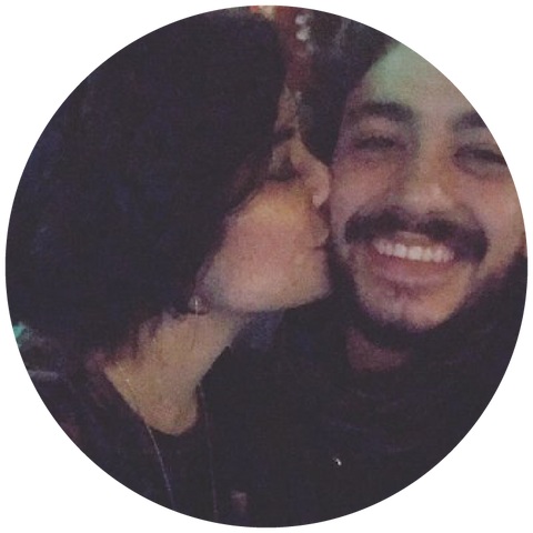 In a warmly lit setting, a woman gently kisses the cheek of a smiling man, radiating joy and affection.