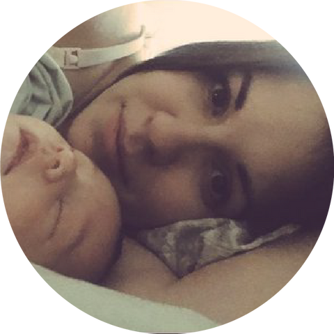 A peaceful scene of a woman and her sleeping baby cuddled together, both facing the camera, creates a heartwarming moment.