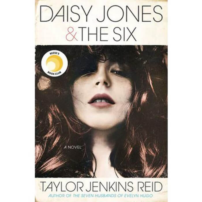 The cover of Daisy Jones & The Six showcases a woman with flowing hair, coupled with the prominent name of bestselling author Taylor Jenkins Reid. The image captures the rock n roll essence at the heart of this captivating novel.