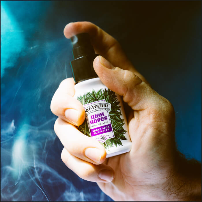 A hand grasps a spray bottle labeled High Hopes adorned with cannabis leaves, enveloped in curling smoke.