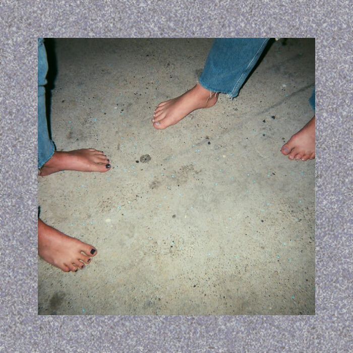 Three people with bare feet and jeans stand casually on a rugged, textured concrete surface, embracing a natural connection to their environment.