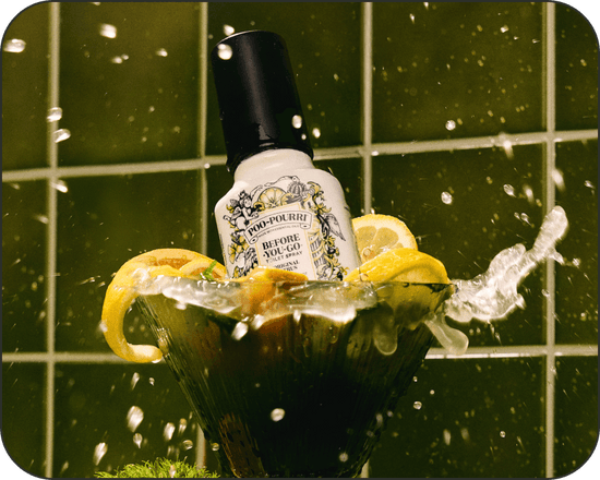 Bottle of Poo~Pourri Original Citrus toilet spray with lemons in a bowl on a green tiled background