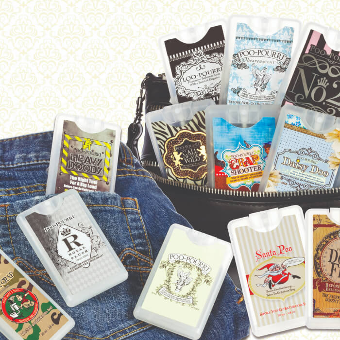 A charming basket holds an assortment of Poo-Pourri spray bottles, one casually resting on denim fabric, adding a touch of freshness to the scene.