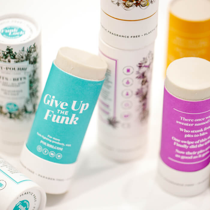 Eco-friendly deodorant sticks, adorned with vibrant labels, are neatly arranged on a white surface.