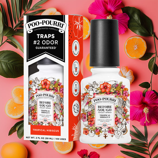 A ~Poo-Pourri “Before You Go” toilet spray in the Tropical Hibiscus scent is displayed alongside its packaging against a decorative orange-pink background, featuring citrus and leaves. The bottle and box have an intricate design with cherubs, toilet paper, and citrus elements, highlighting the ingredients. The packaging emphasizes the product’s ability to trap odors before they start, with key details such as “100 Uses,” “No Aerosols,” and “Essential Oils” visible.