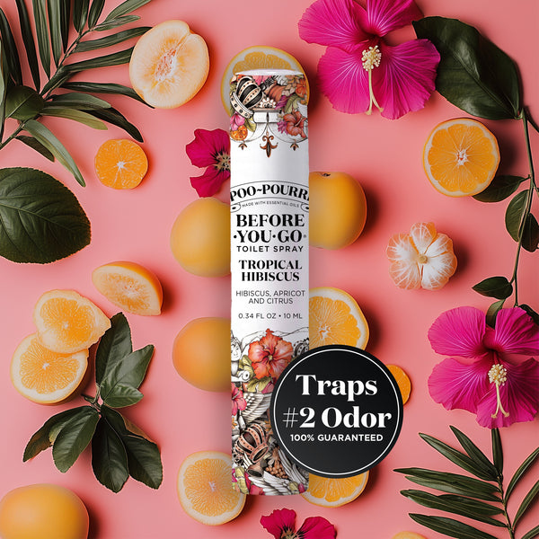 A vibrant product image of Poo-Pourri “Before You Go” toilet spray in the “Tropical Hibiscus” scent, featuring hibiscus, apricot, and citrus. The spray bottle is centrally placed against a bright prink background, surrounded by fresh lemons, green leaves, and hibiscus. A black circular label highlights the product’s promise to “Trap #2 Odor 100% Guaranteed”.