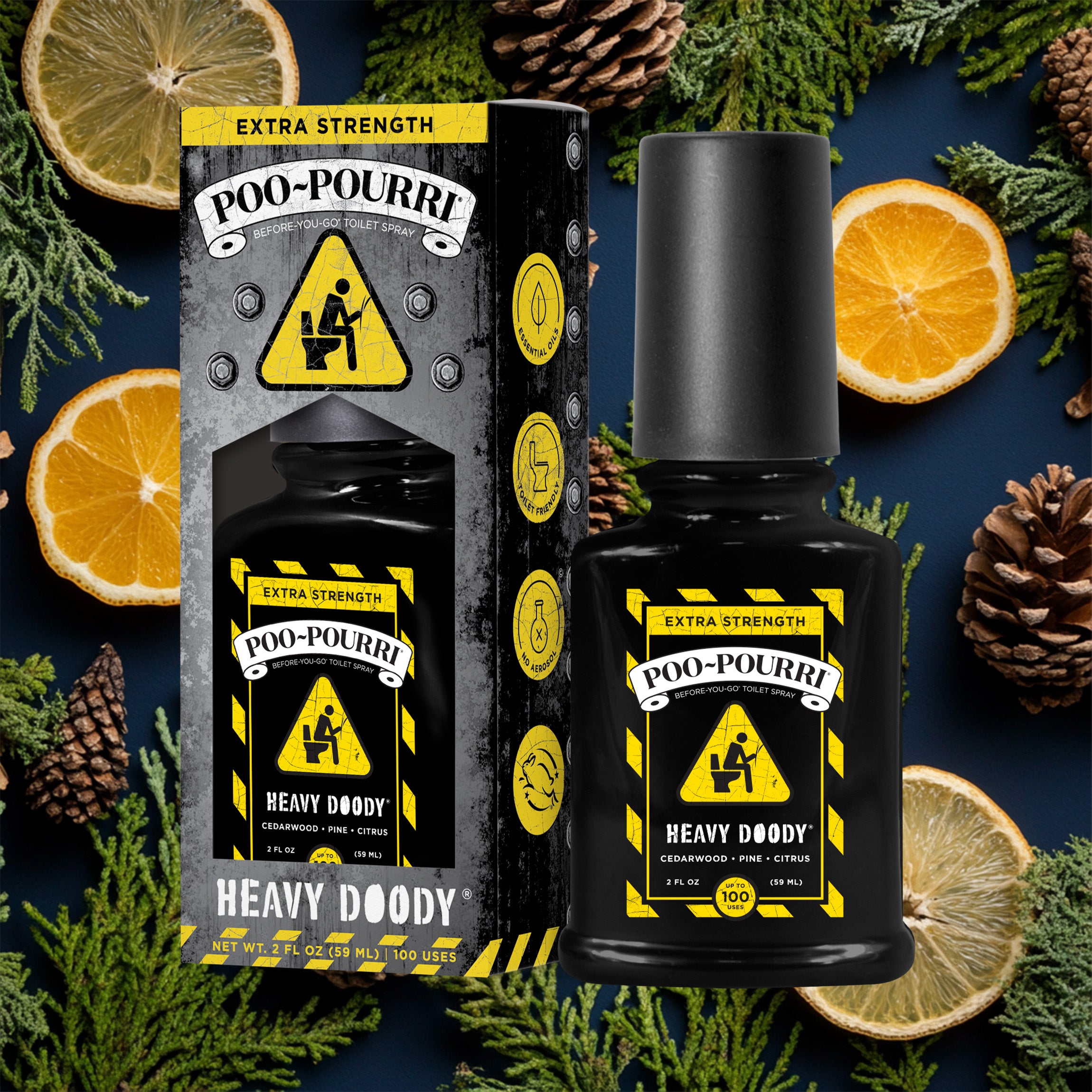 A ~Poo-Pourri “Before You Go” toilet spray in the Heavy Doody scent is displayed alongside its packaging against a decorative dark blue background, featuring lemons and pine cones. The bottle and box have an intricate design with yellow caution pattern, and yellow triangle sign featuring a stickman sitting on a toilet.. The packaging emphasizes the product’s ability to trap odors before they start, with key details such as “100 Uses,” “No Aerosols,” and “Essential Oils” visible.