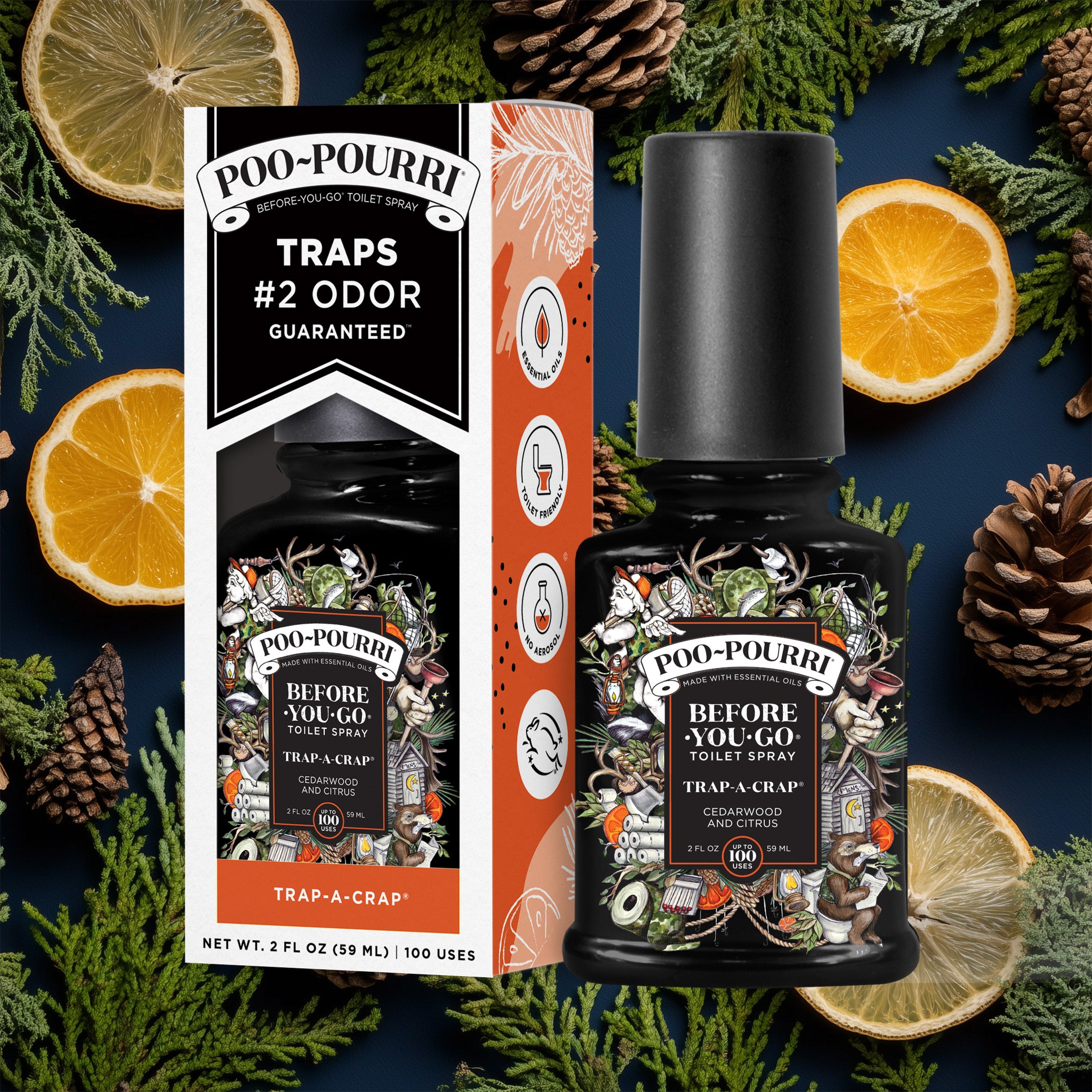 A ~Poo-Pourri “Before You Go” toilet spray in the Trap-A-Crap scent is displayed alongside its packaging against a decorative dark blue background, featuring lemons and pine cones. The bottle and box have an intricate design with cherubs, toilet paper, and camping elements. The packaging emphasizes the product’s ability to trap odors before they start, with key details such as “100 Uses,” “No Aerosols,” and “Essential Oils” visible.