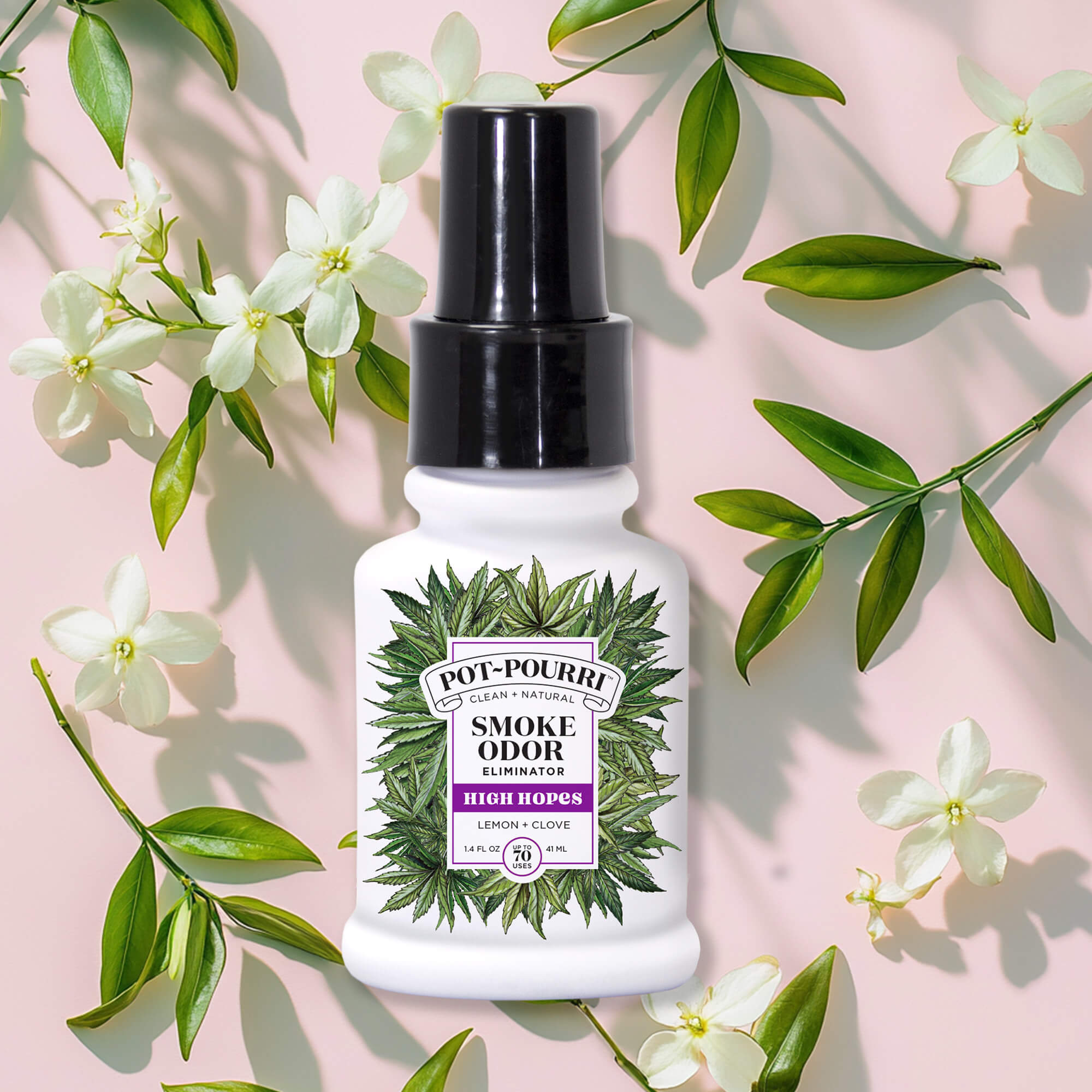 The High Hopes - Pot~Pourri Smoke Refresher by ~Pourri, with its fresh & clean formula, is set amid green leaves and white flowers on a pink background.