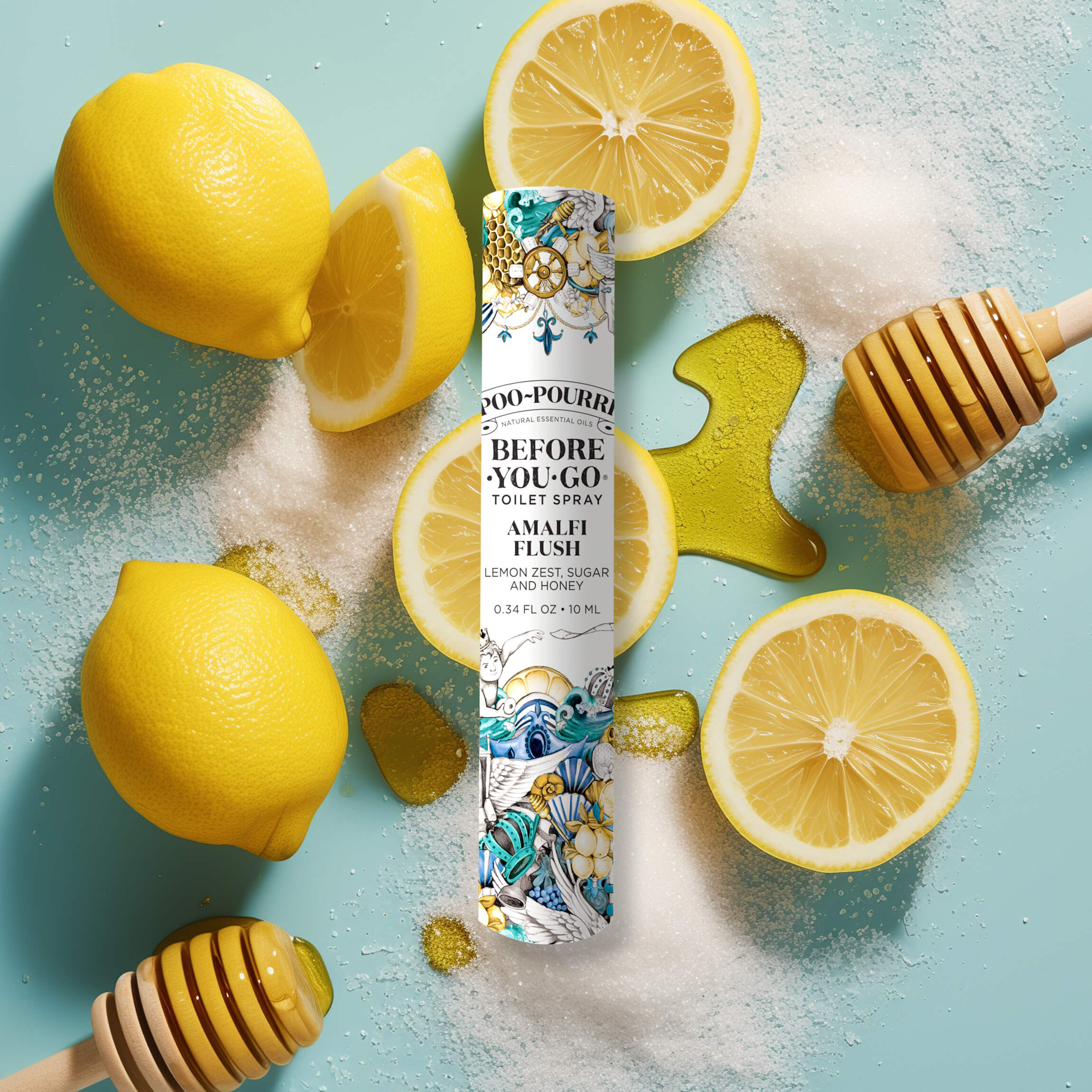 An Amalfi Flush 10ml - Poo~Pourri Toilet Spray by ~Pourri is set against a blue background, flanked by zesty lemon slices, sugar, and honey dippers, evoking a fresh ambiance.