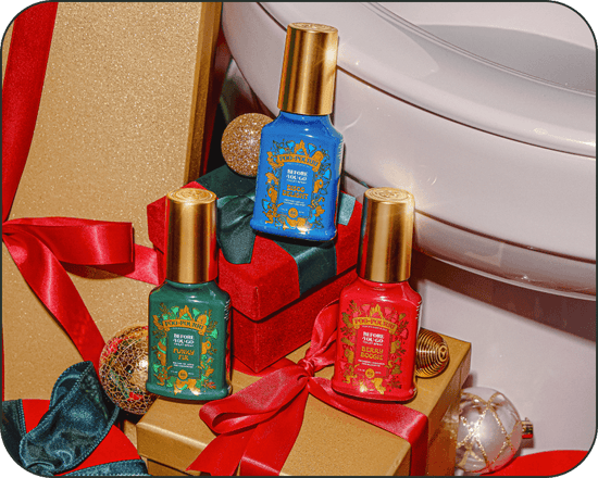 Three bottles of Poo~Pourri holiday-themed scents with gold caps on a decorative background with ribbons and gift boxes.