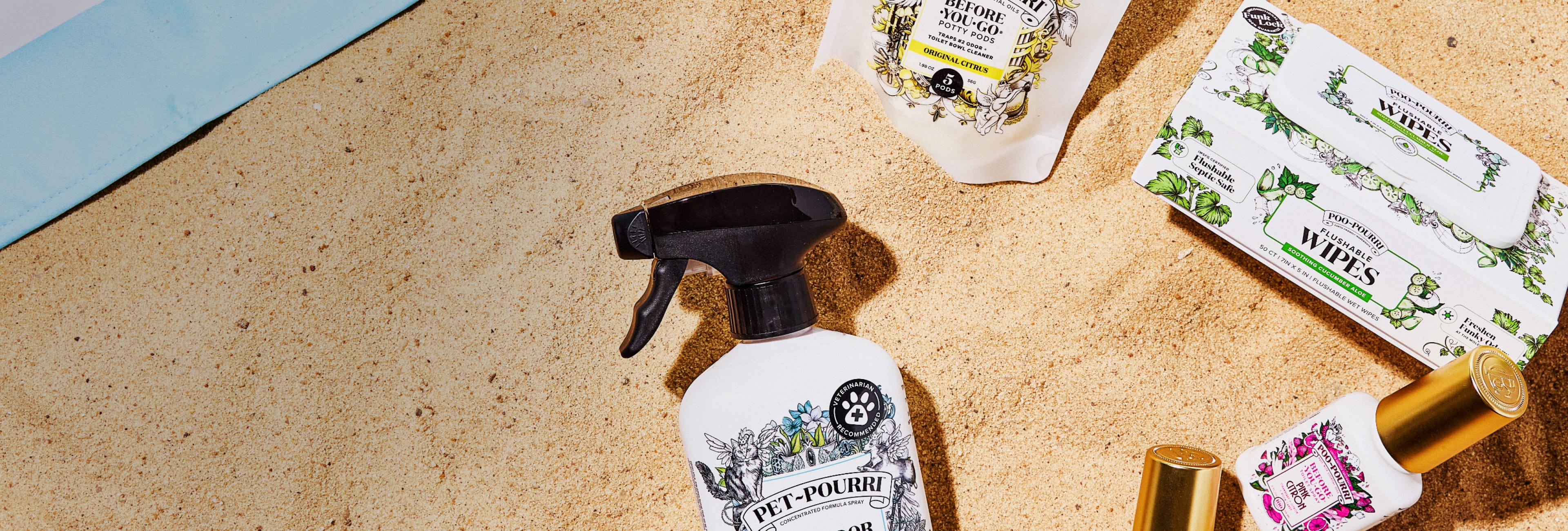 Pourri products laying on sand with a blue towel in the background