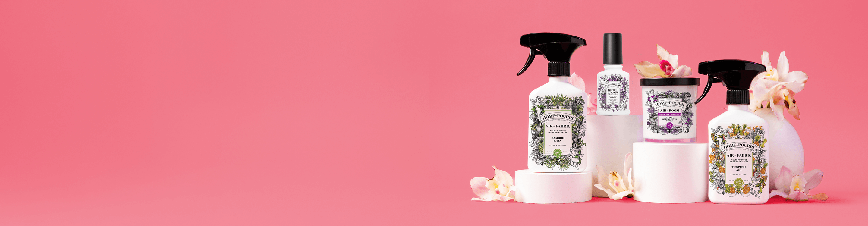 Home-Pourri & Poo~Pourri sprays for Mother’s Day, displayed on white pedestals against a pink background, surrounded by white and pink flowers.