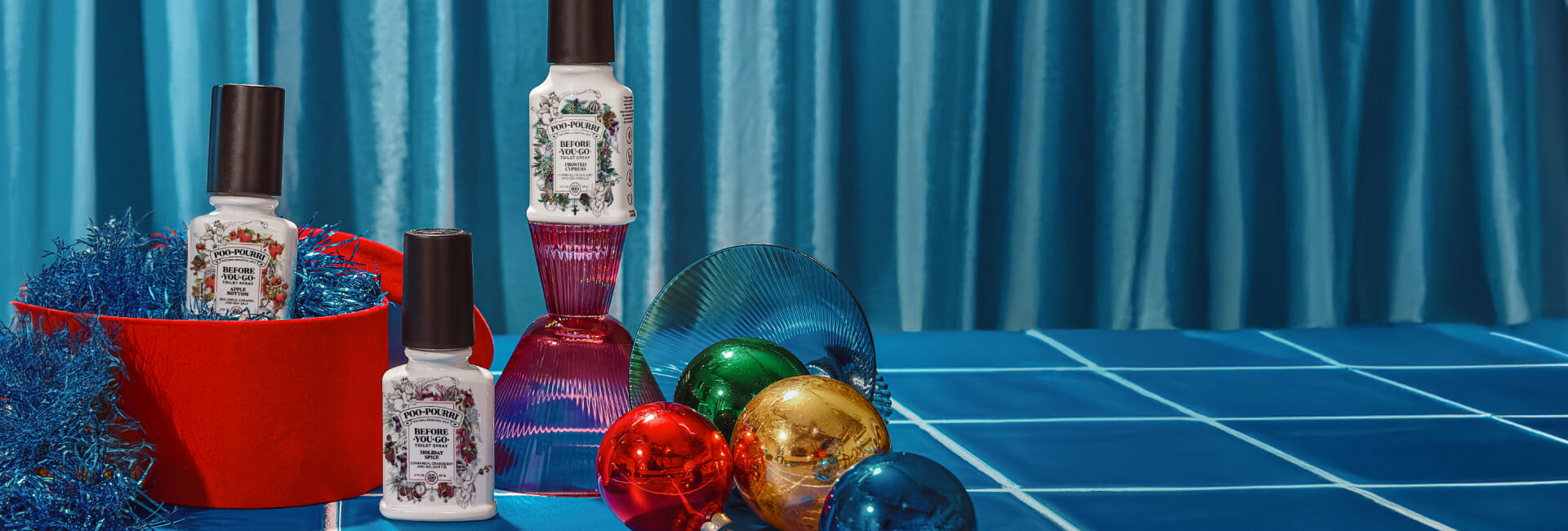 Set of Poo~Pourri products on a blue tiled surface with a blue curtain background