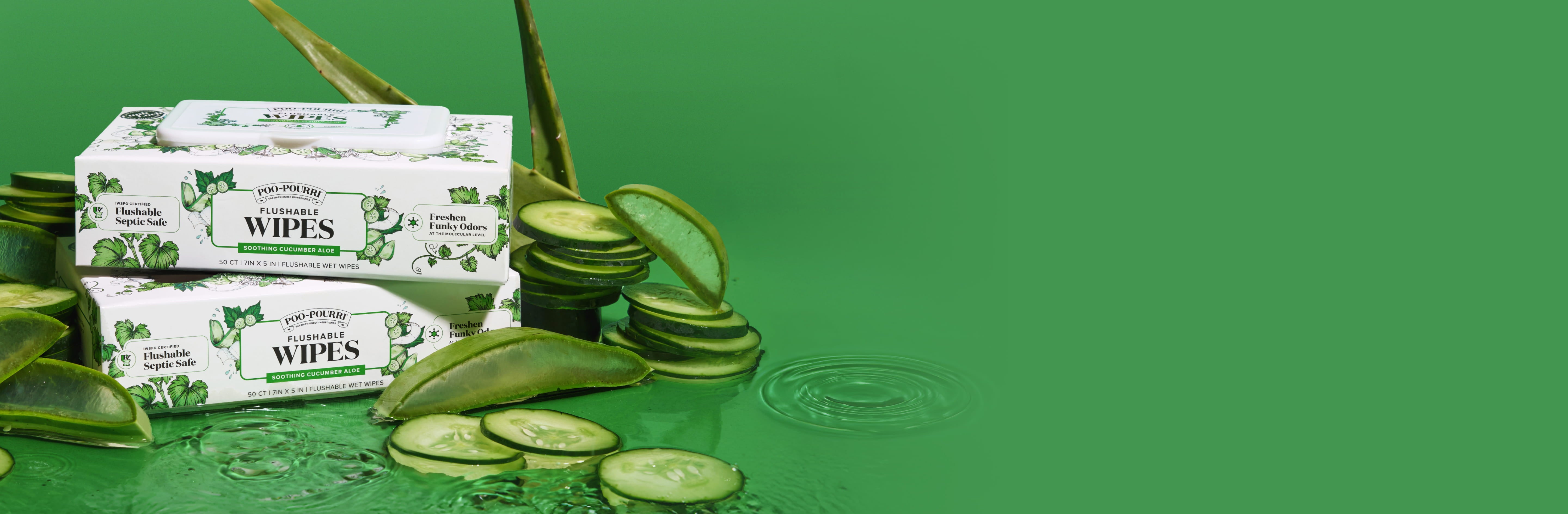 Two packs of Poo~Pourri cucumber aloe flushable wipes on water with cucumber slices, aloe leaves, on a green background