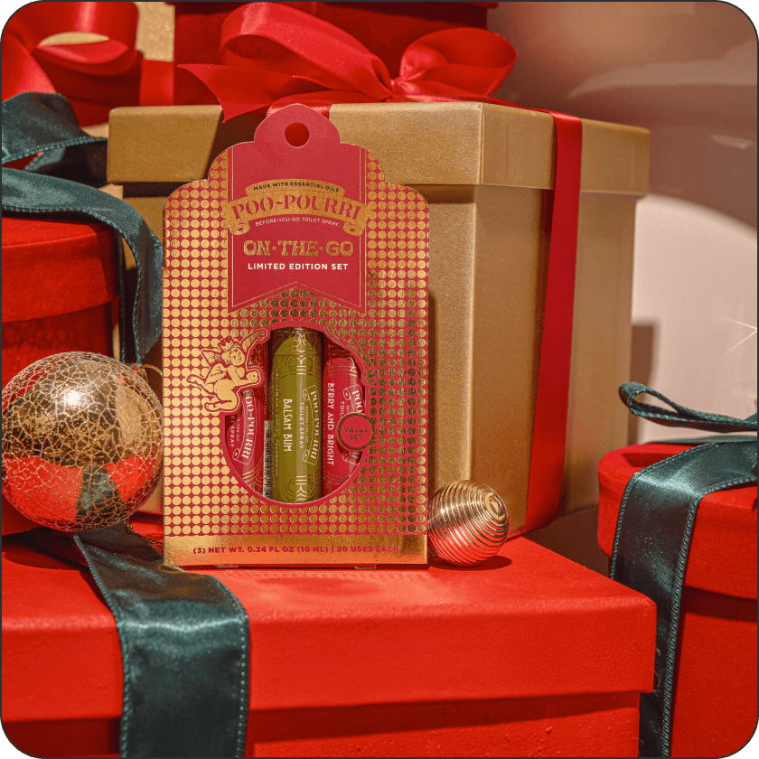 Poo-Pourri on-the-go set in a decorative box with red and gold packaging, surrounded by wrapped presents.
